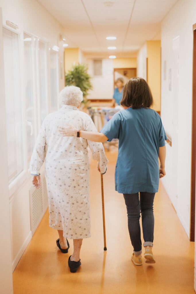 une femme qui aide une femme agée à marcher